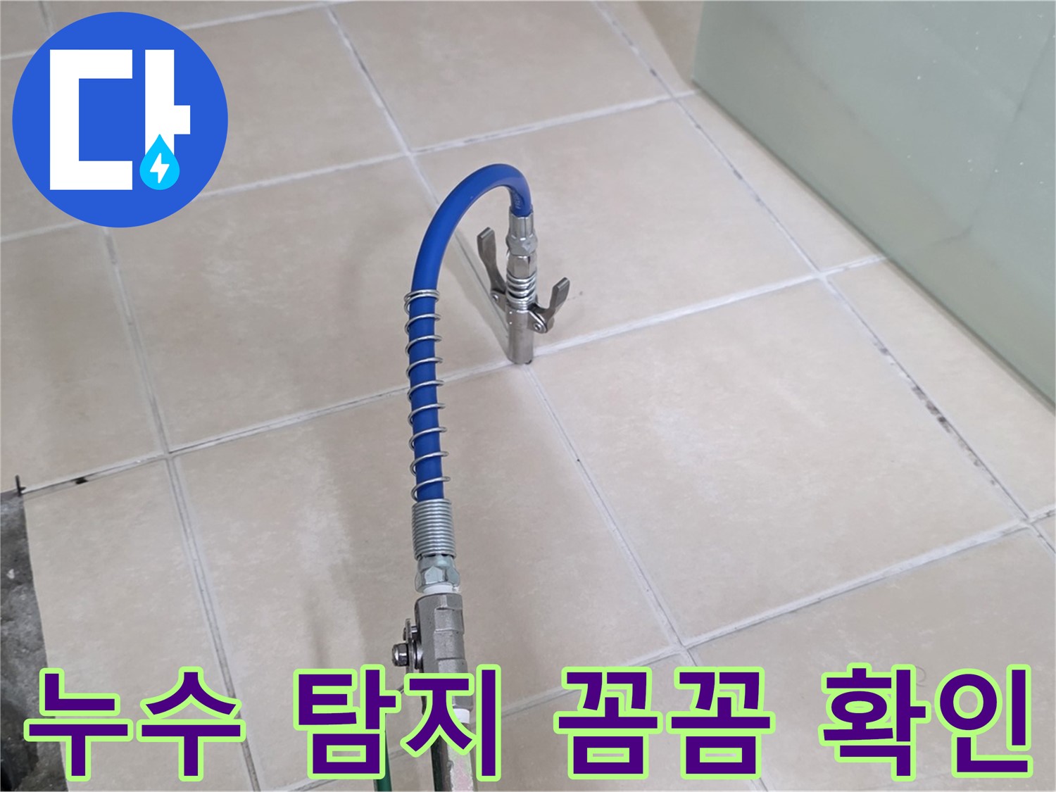 화장실 바닥 타일 위로 연결된 파란색 호스 및 배수구 부근