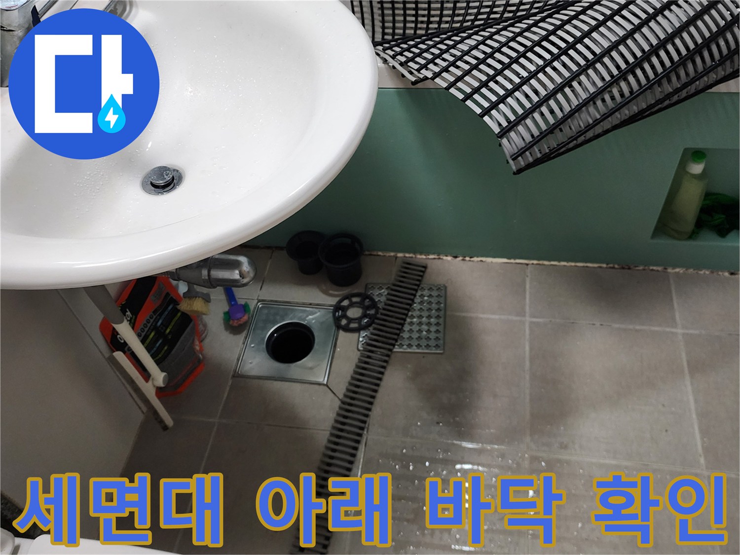 욕실 세면대 밑 배수구와 주변 타일의 상세 모습입니다.