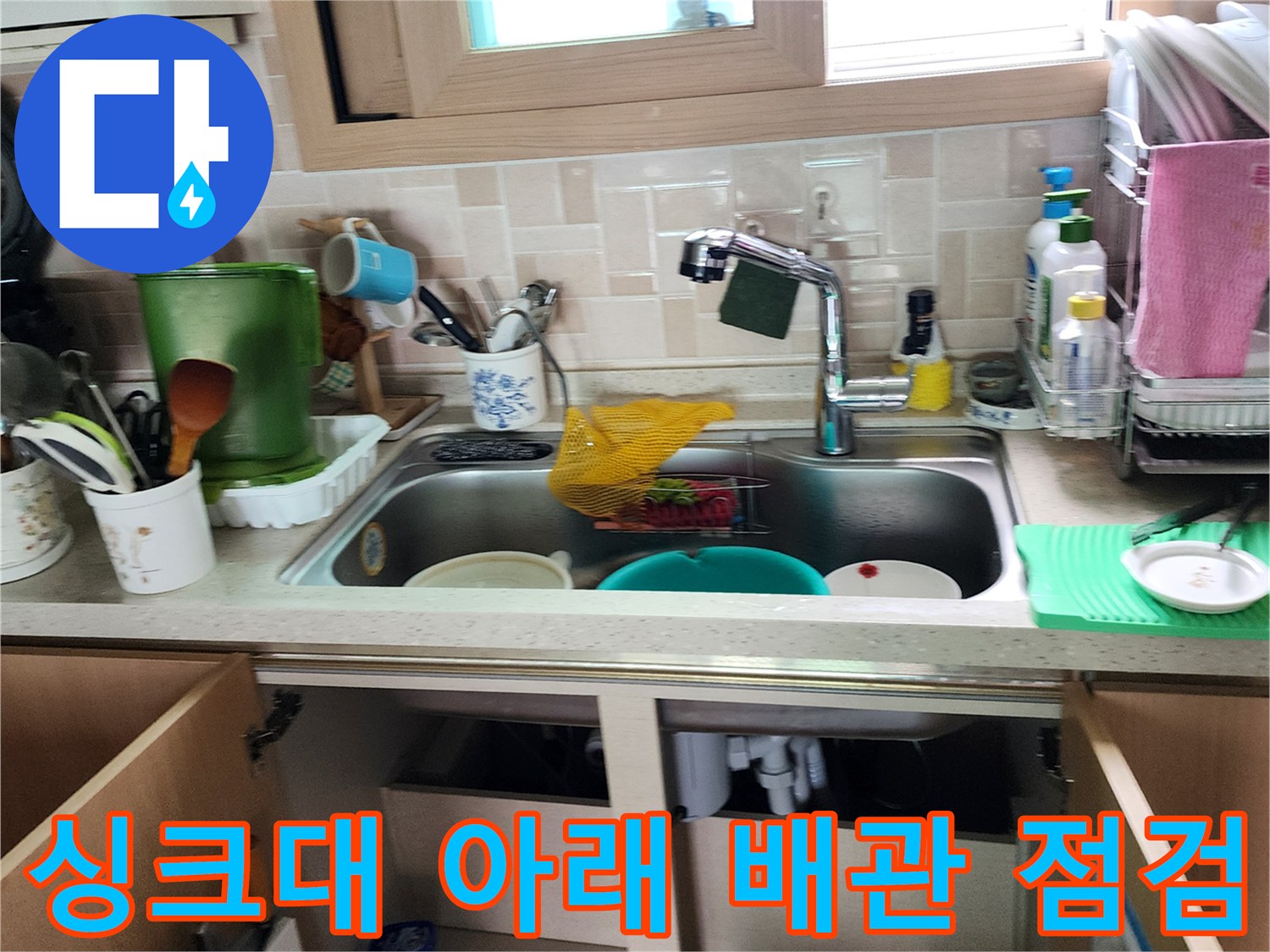 싱크대 하부장 내부의 복잡한 배관 연결 상태 확인