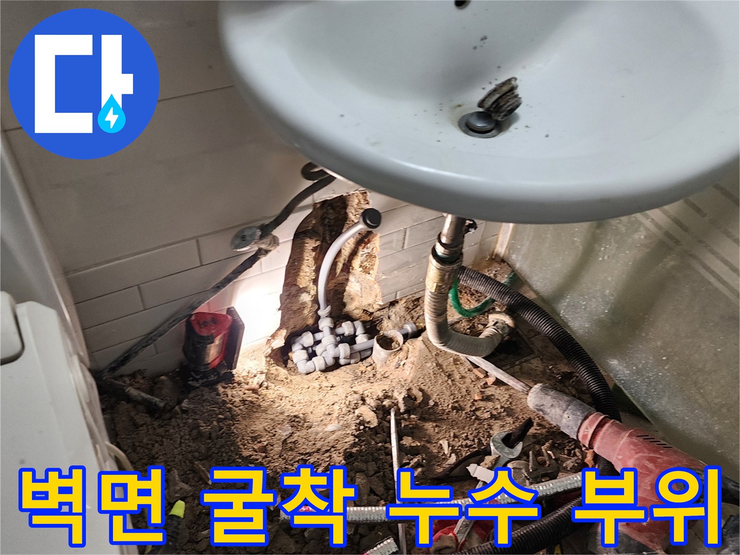 세면대 아래 타일 제거-노출된 배관과 젖은 주변 토사