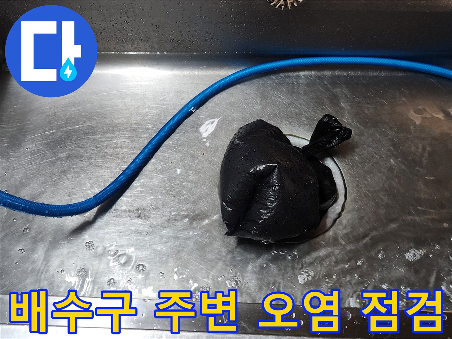 스테인리스 싱크대 내부의 파란색 호스와 검은 비닐 뭉치