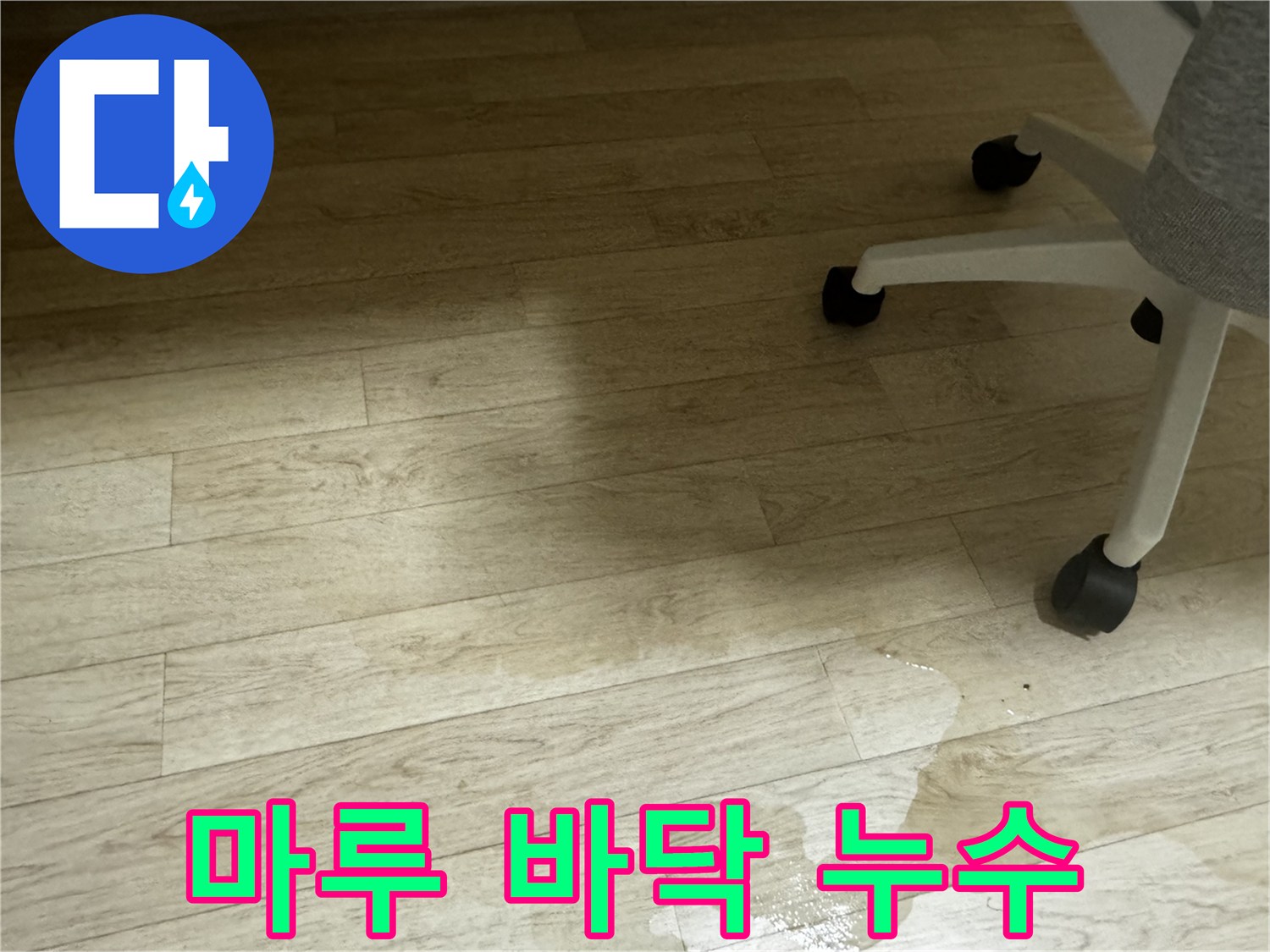 마루 바닥에 누수가 발생하여 물이 스며든 모습 - 변색과 얼룩이 보입니다.