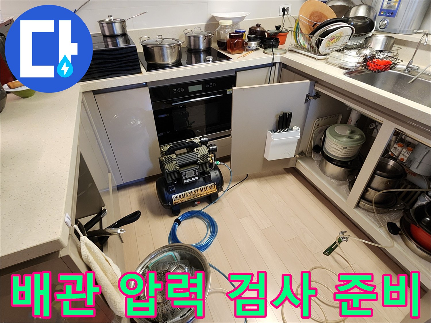 싱크대 아래쪽 배관 진단을 위해 연결된 공압 장비와 호스들