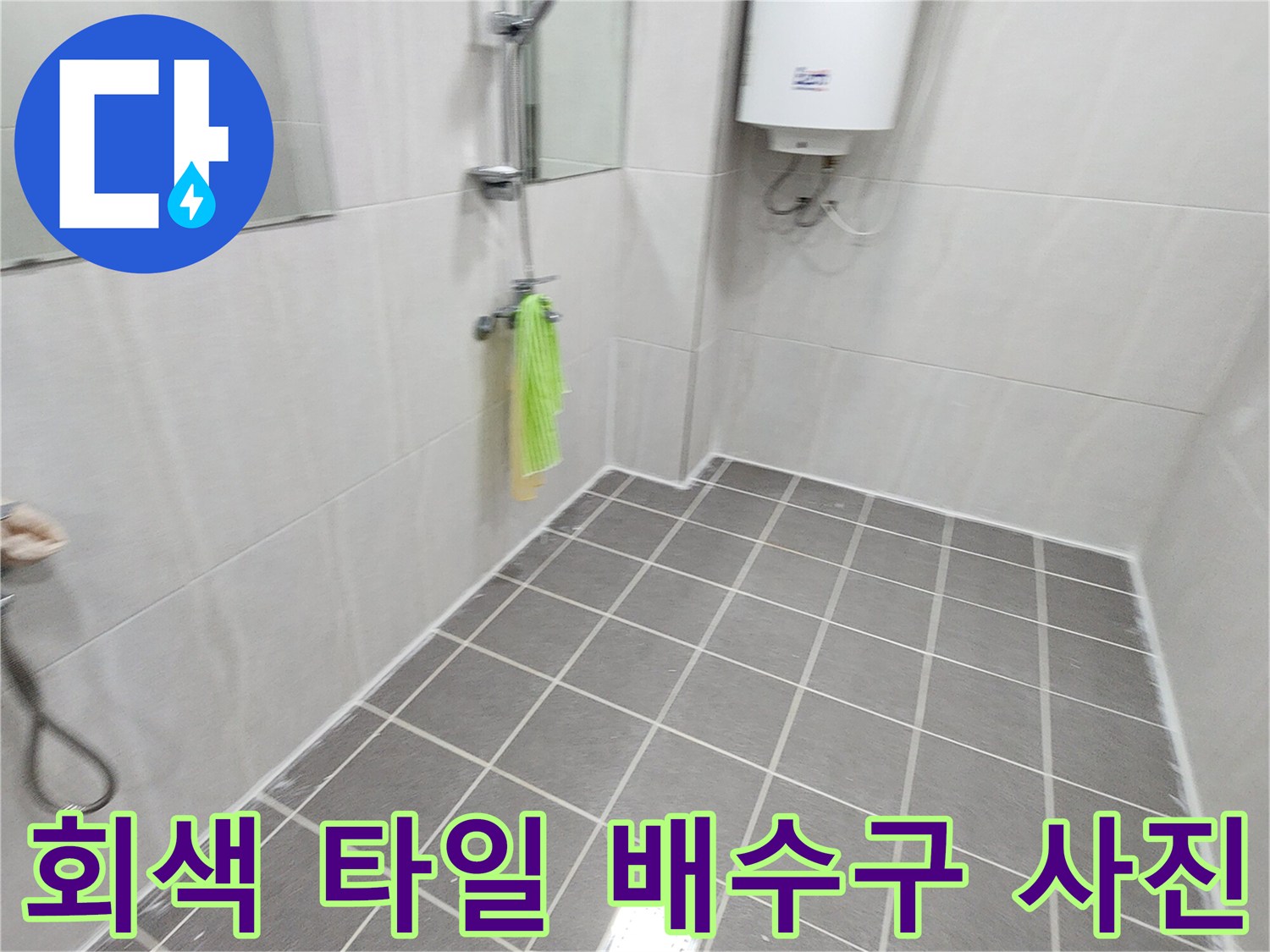 욕실 내부의 회색 타일과 금속 배수구 덮개 이미지입니다.