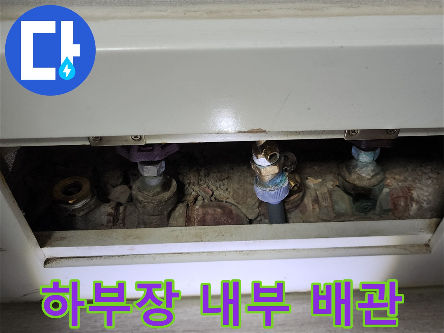 주방 하부장 아래에 위치한 복잡한 분배기 및 밸브 구조