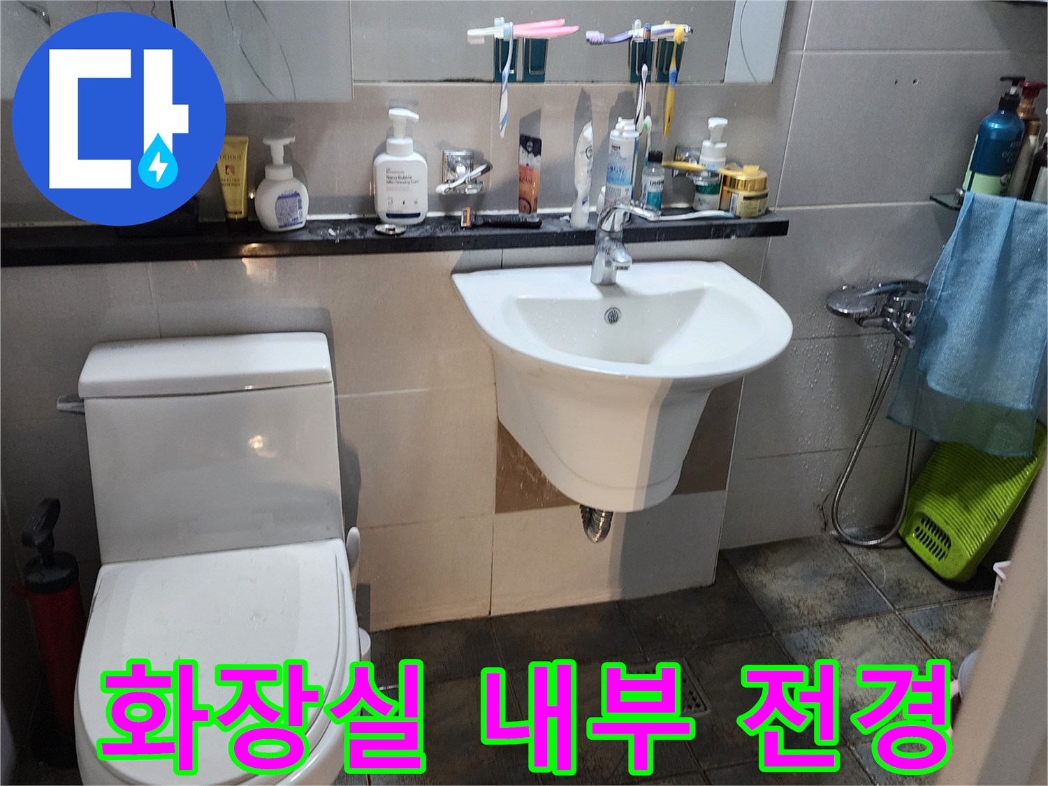 변기와 세면대가 배치된 화장실의 타일 벽면 모습