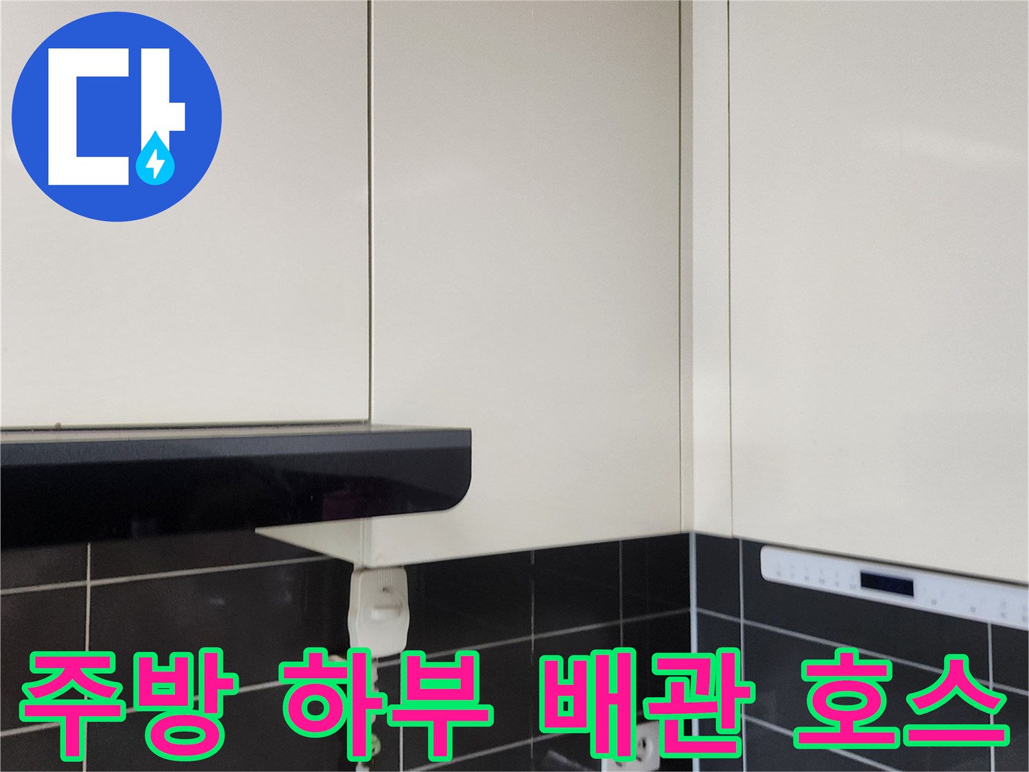 하얀색 상부장 아래 싱크대 수전 연결 호스와 콘센트 부위