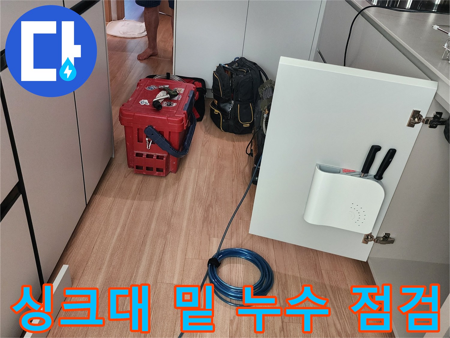 싱크대 하부장 문을 열고 내부 배관 상태를 관찰하는 장면
