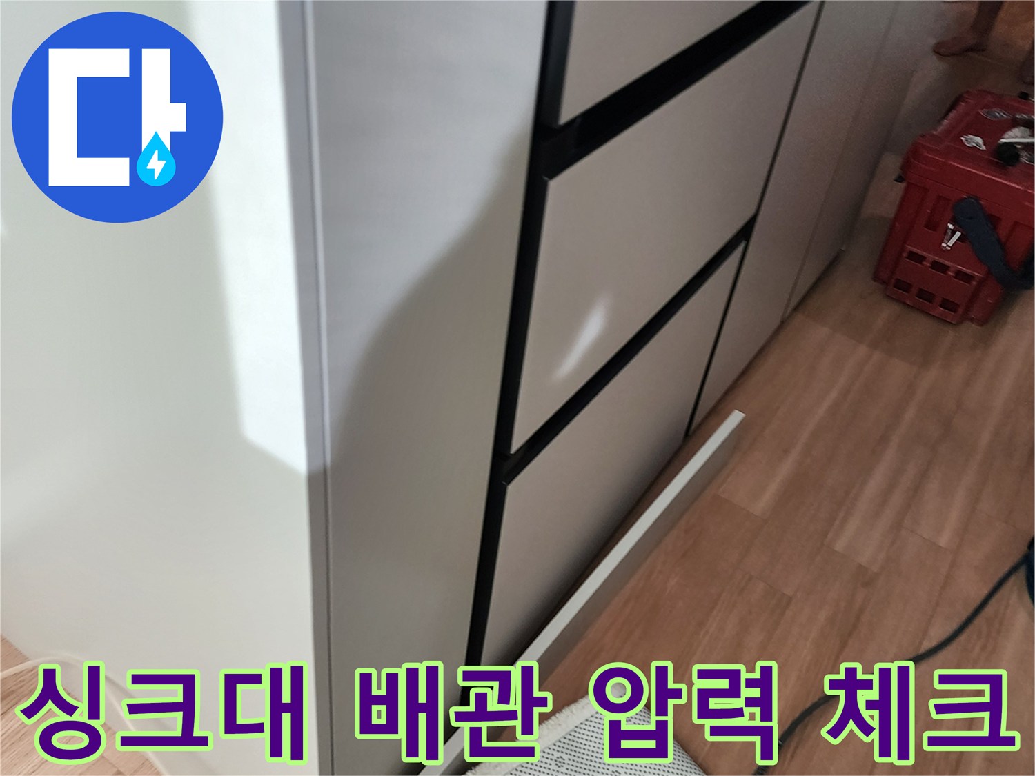 주방 수납장 아래 공간에 설치된 배관과 측정용 호스 연결 상태
