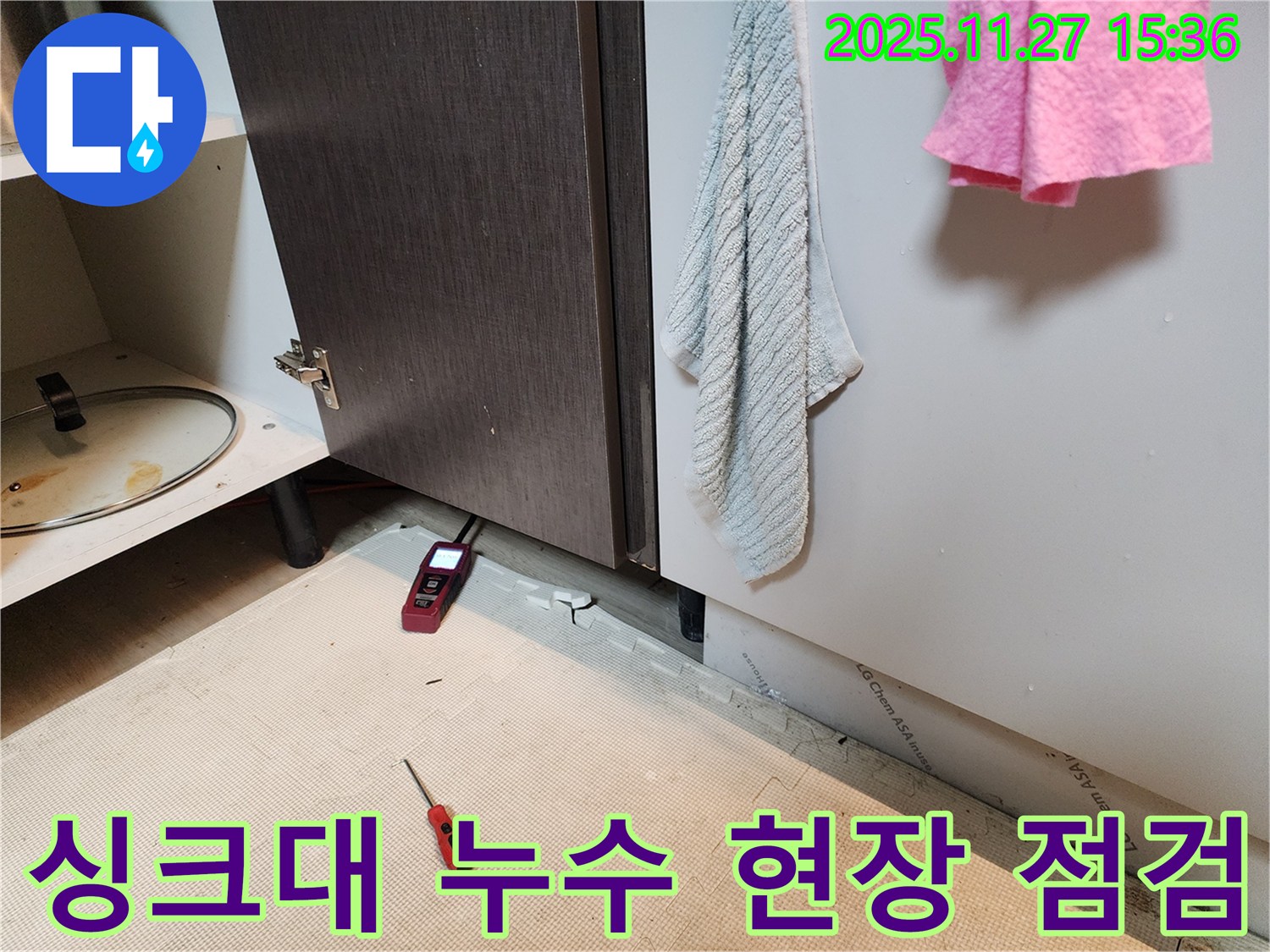 싱크대 하부에서 누수 전문가가-습도 측정기와 도구를 사용하여-현장을 꼼꼼하게 점검하고 있습니다.