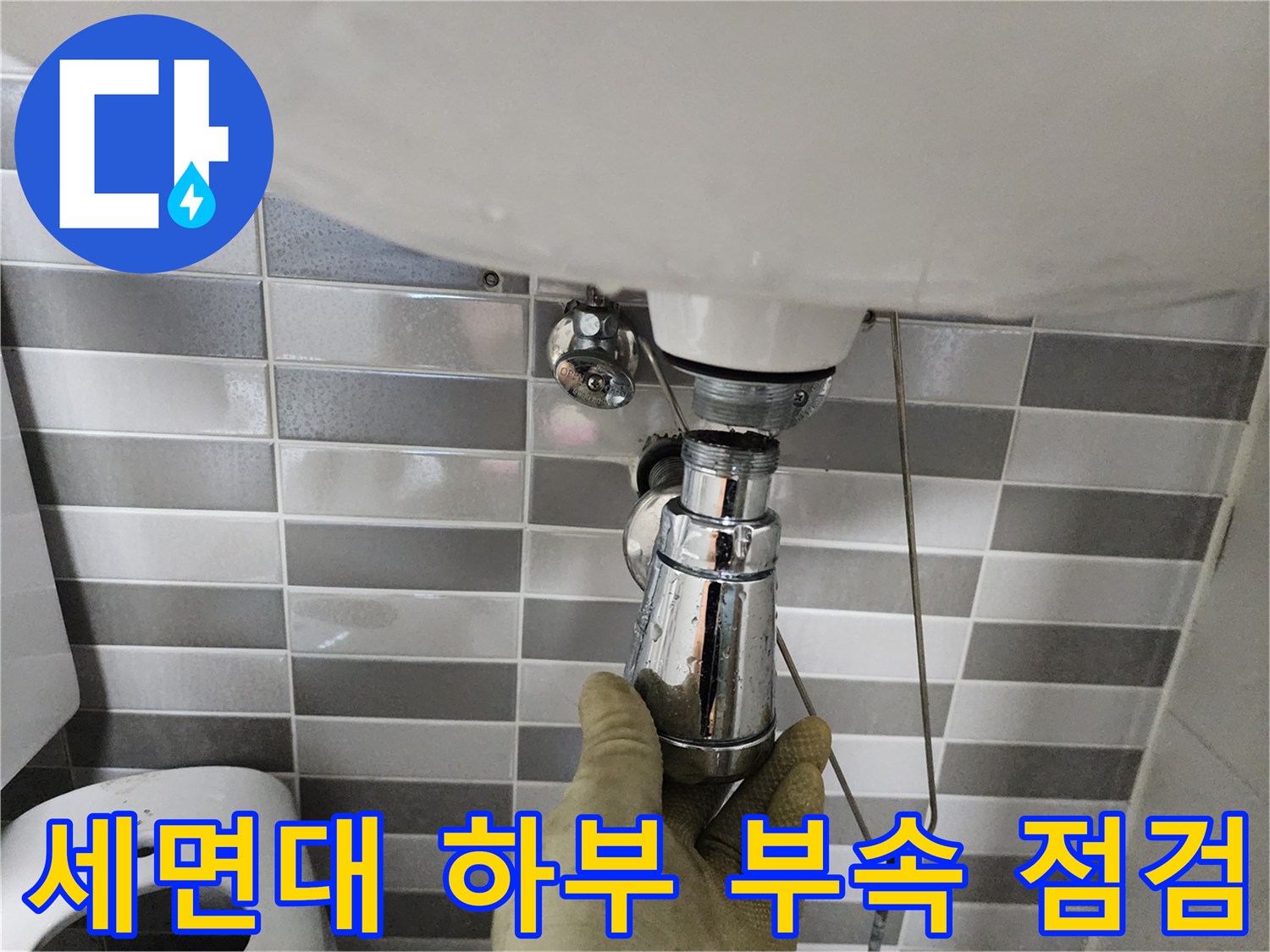 세면대 아래쪽 크롬 도금 배관의 연결 상태를 손으로 확인 중