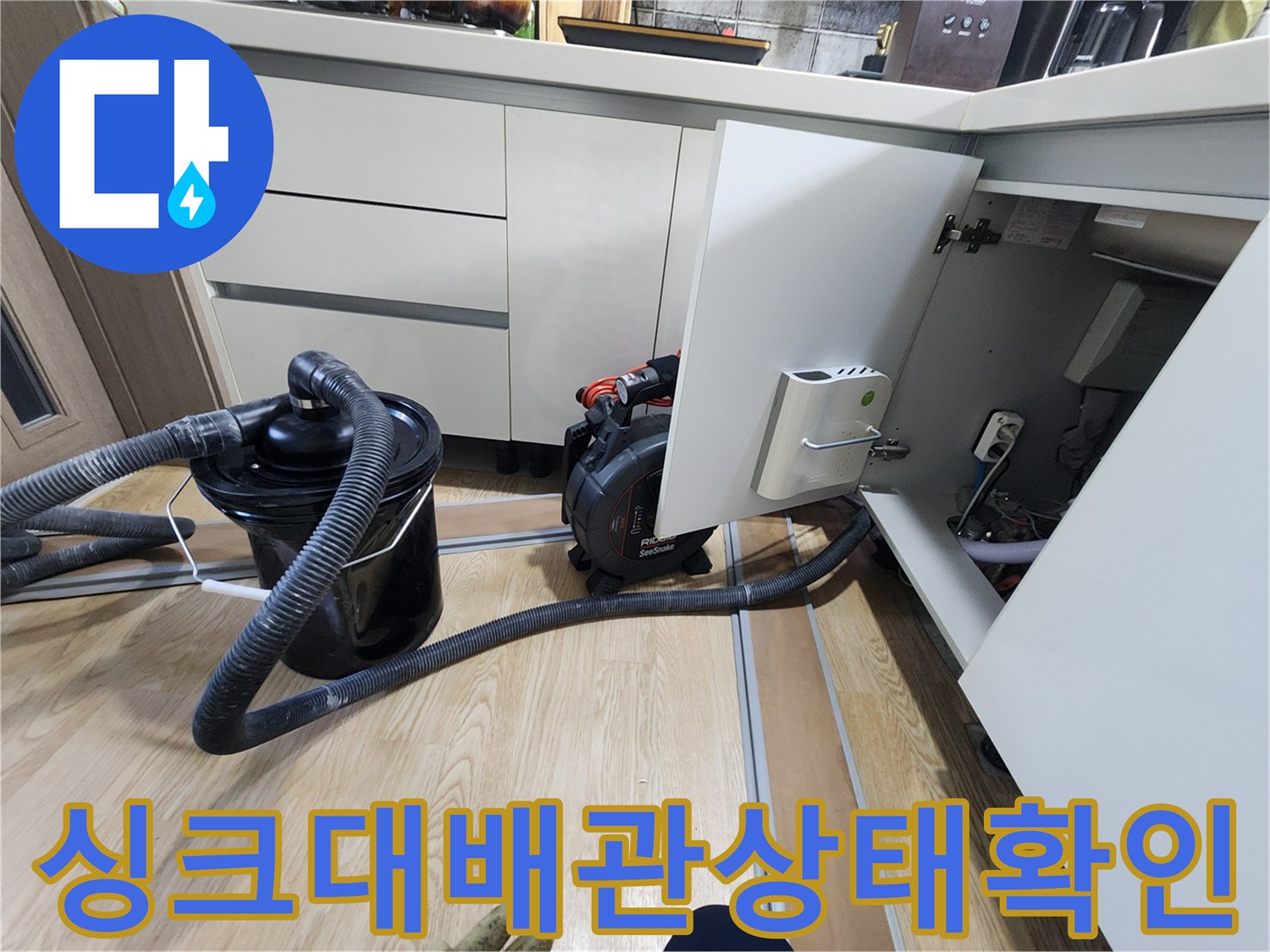 열려 있는 싱크대 하부장과 연결된 배수 호스 모습