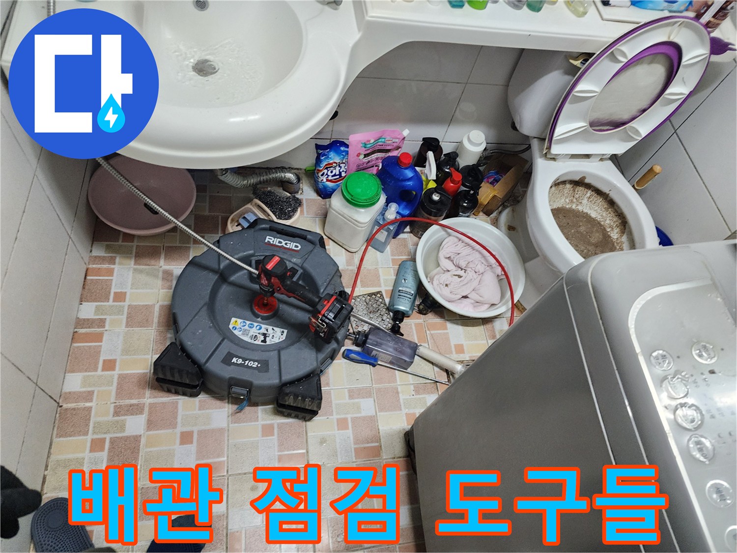 욕실 바닥 타일 위에 놓인 배관 내시경과 각종 청소용 장비 세트
