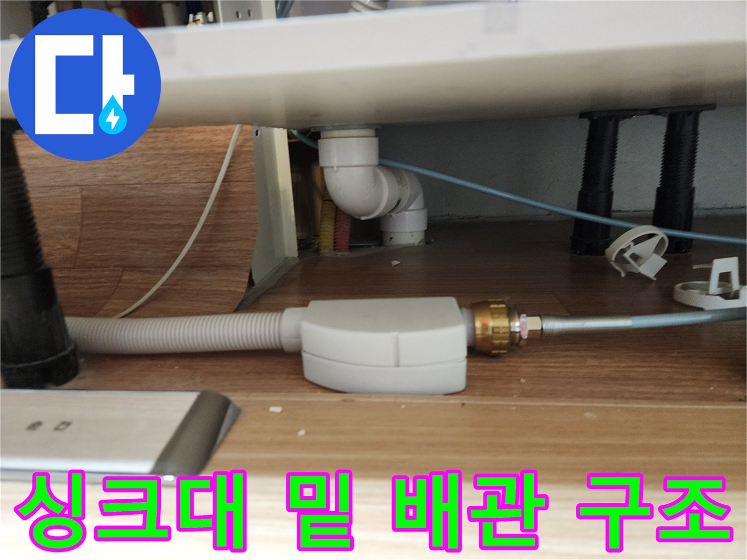 싱크대 하부 공간에 노출된 흰색 배관과 호스 연결 부위