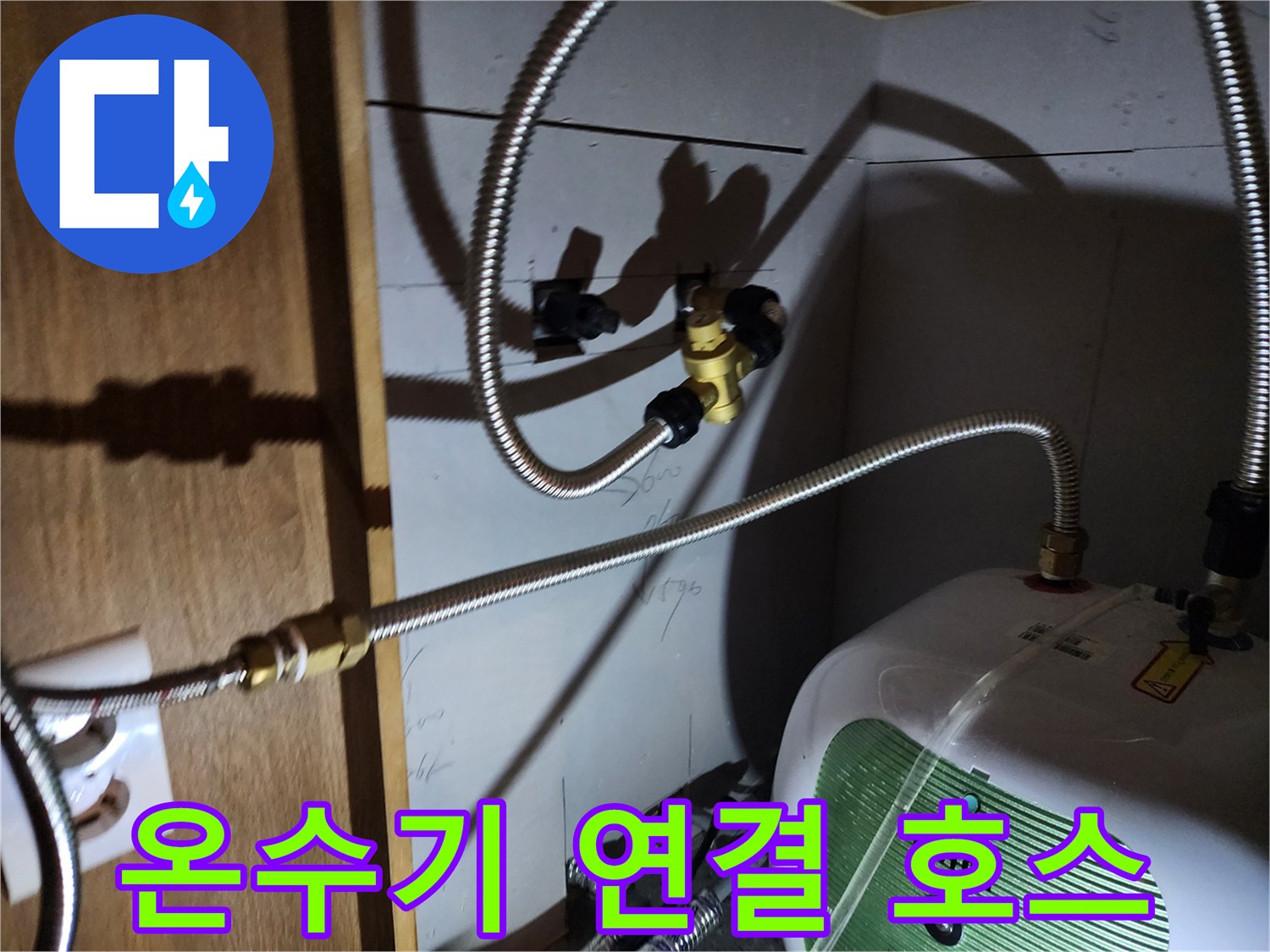 전기 온수기와 벽면 밸브를 이어주는 은색 금속 배관 부위