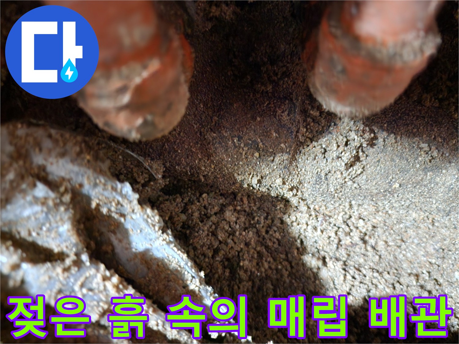 매립된 오렌지색 보온재 배관 주변의 젖은 토양 상태