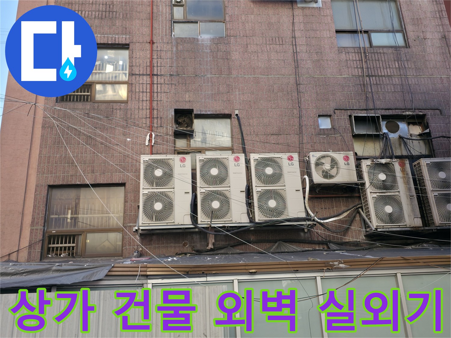 상가 건물 외벽에 설치된 에어컨 실외기와 배관 모습입니다.