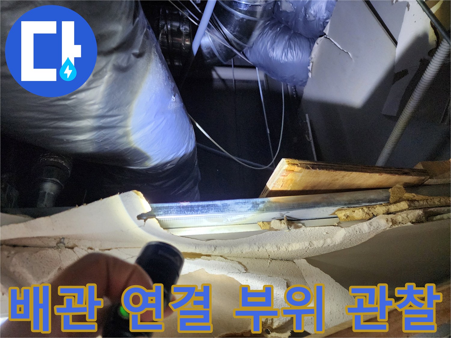 손전등으로 비춘 배관의 틈새와 주변 습기 상태