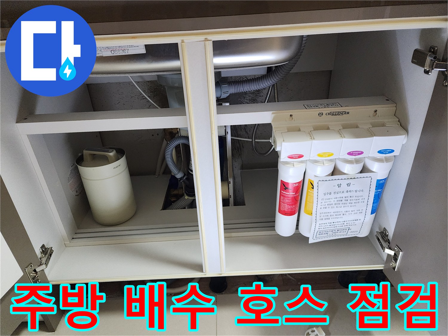 싱크대 하부장 내부의 정수 필터와 굴곡진 배수 호스 연결 부위