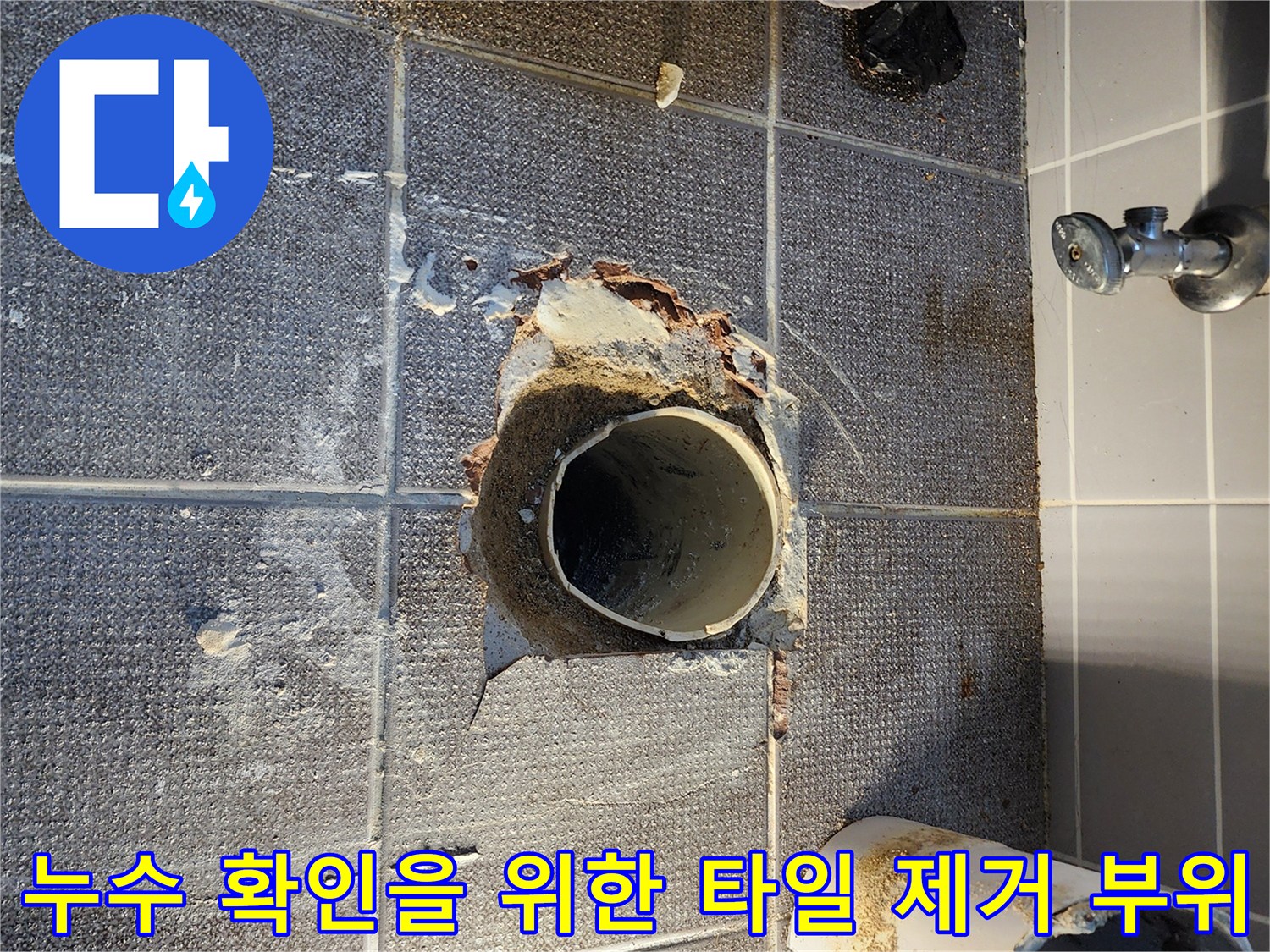 배관 주변의 깨진 타일과 노출된 하수구 관로