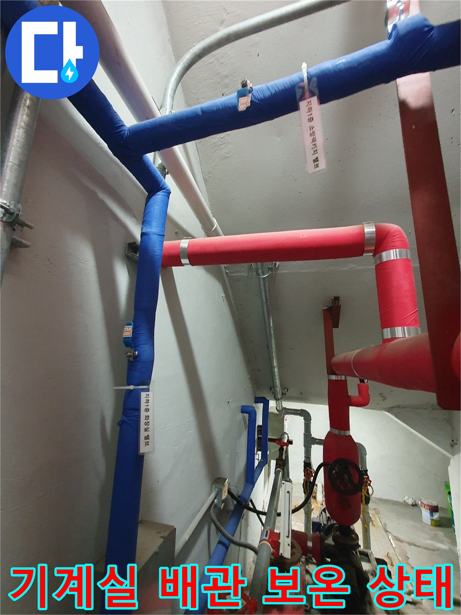 파란색과 빨간색 보온재로 마감된 기계실 내부 배관 모습입니다.