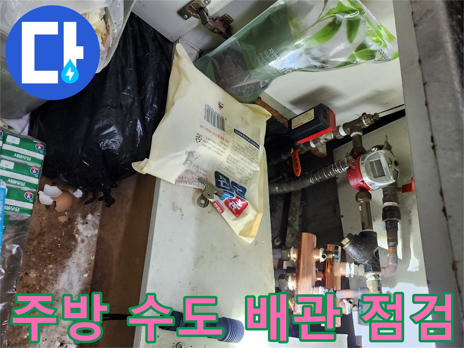 손전등으로 비춘 싱크대 하단 배관의 연결 부위 상세 사진