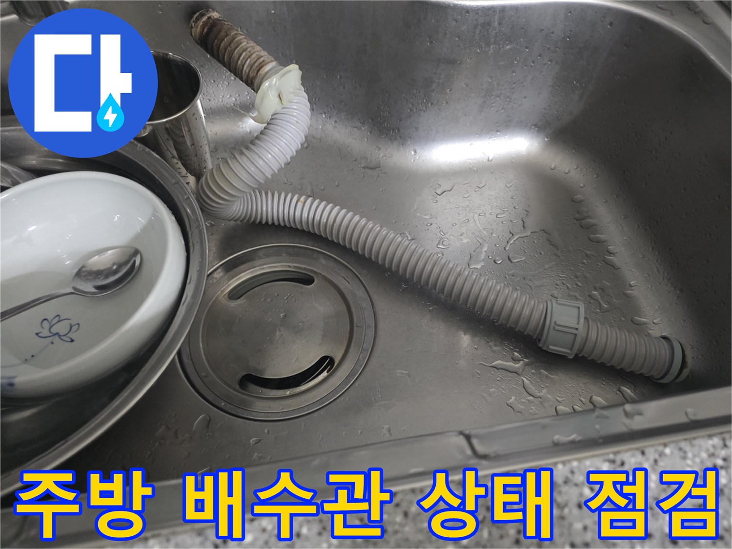 싱크볼 내부의 스테인리스 배수구와 회색 주름 호스