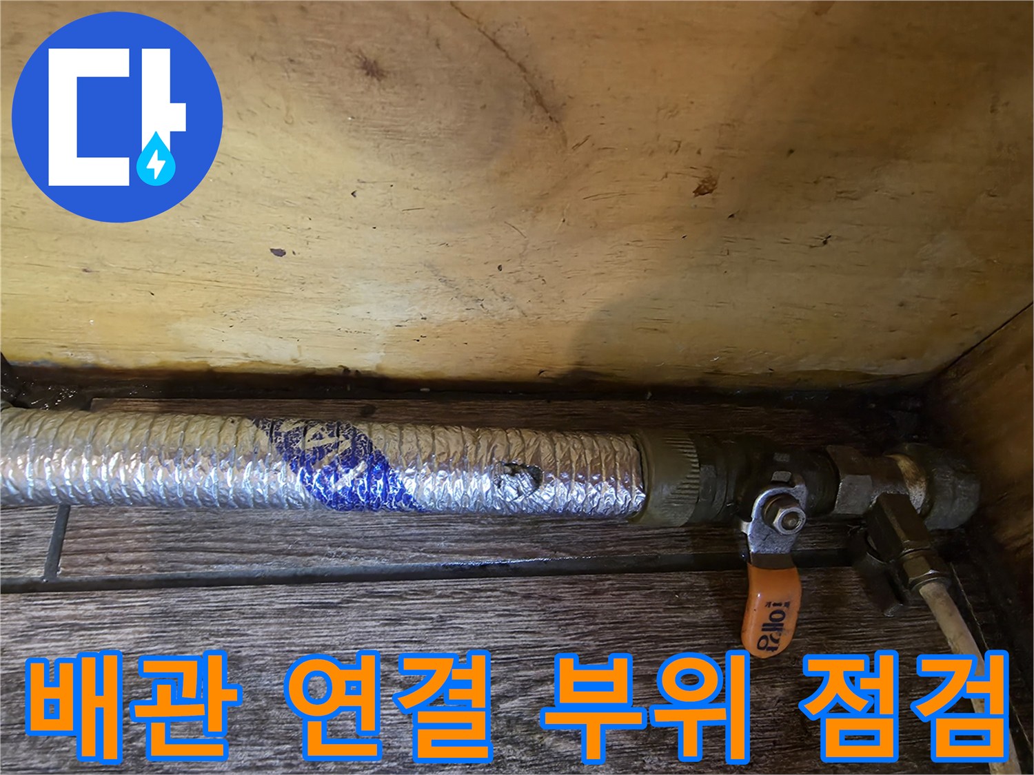 은박 보온재로 덮인 배관과 주황색 밸브의 근접 촬영