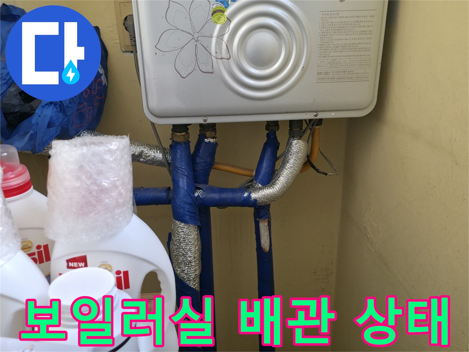 보일러 아래에 설치된 파란색 배관과 은색 보온재