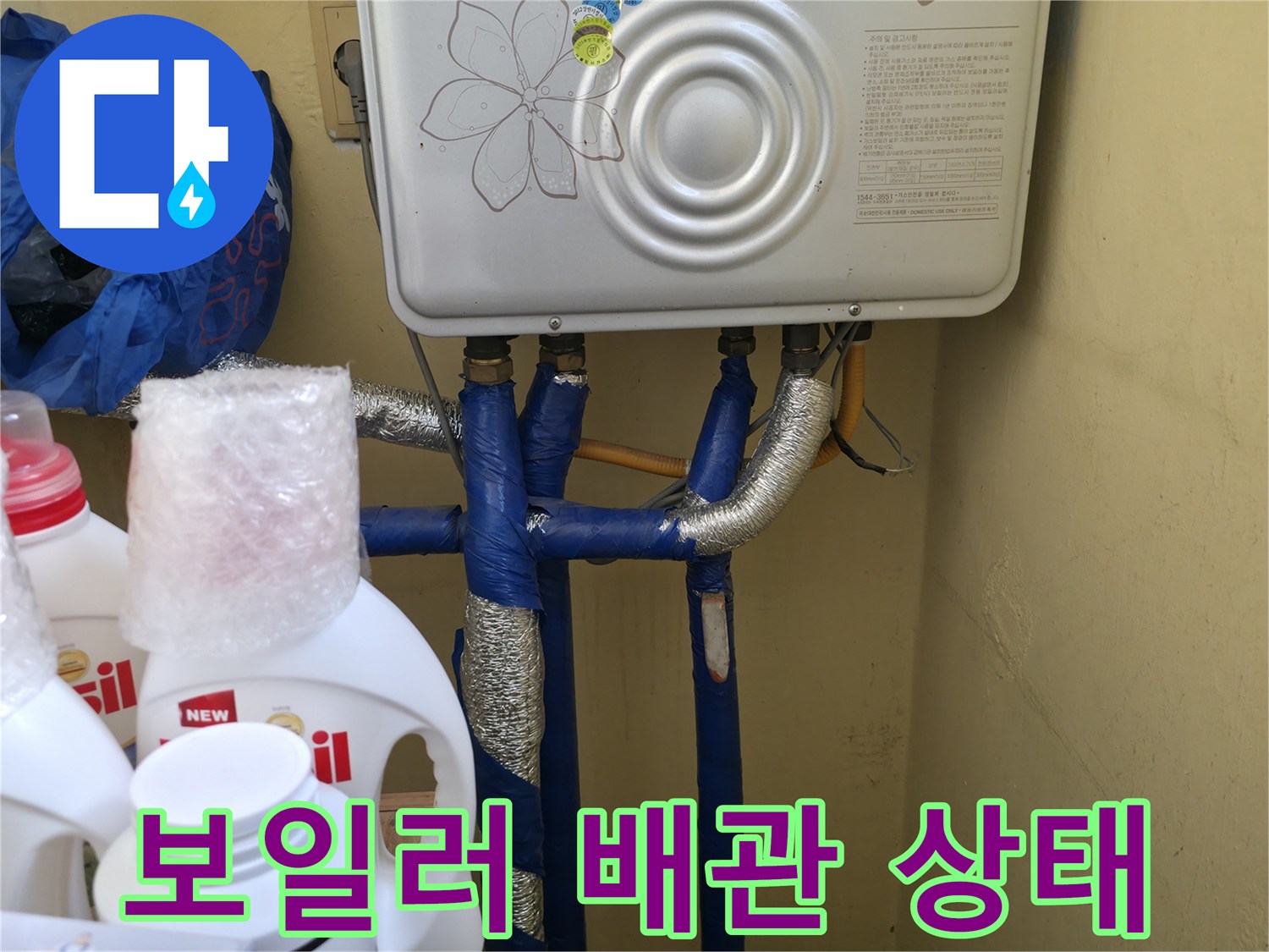 보일러 하단에 연결된 파란색 배관과 보온재 마감 상태