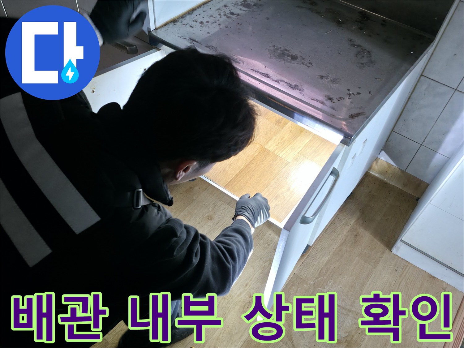 싱크대 아래 배관 입구를 면밀히 관찰하는 모습