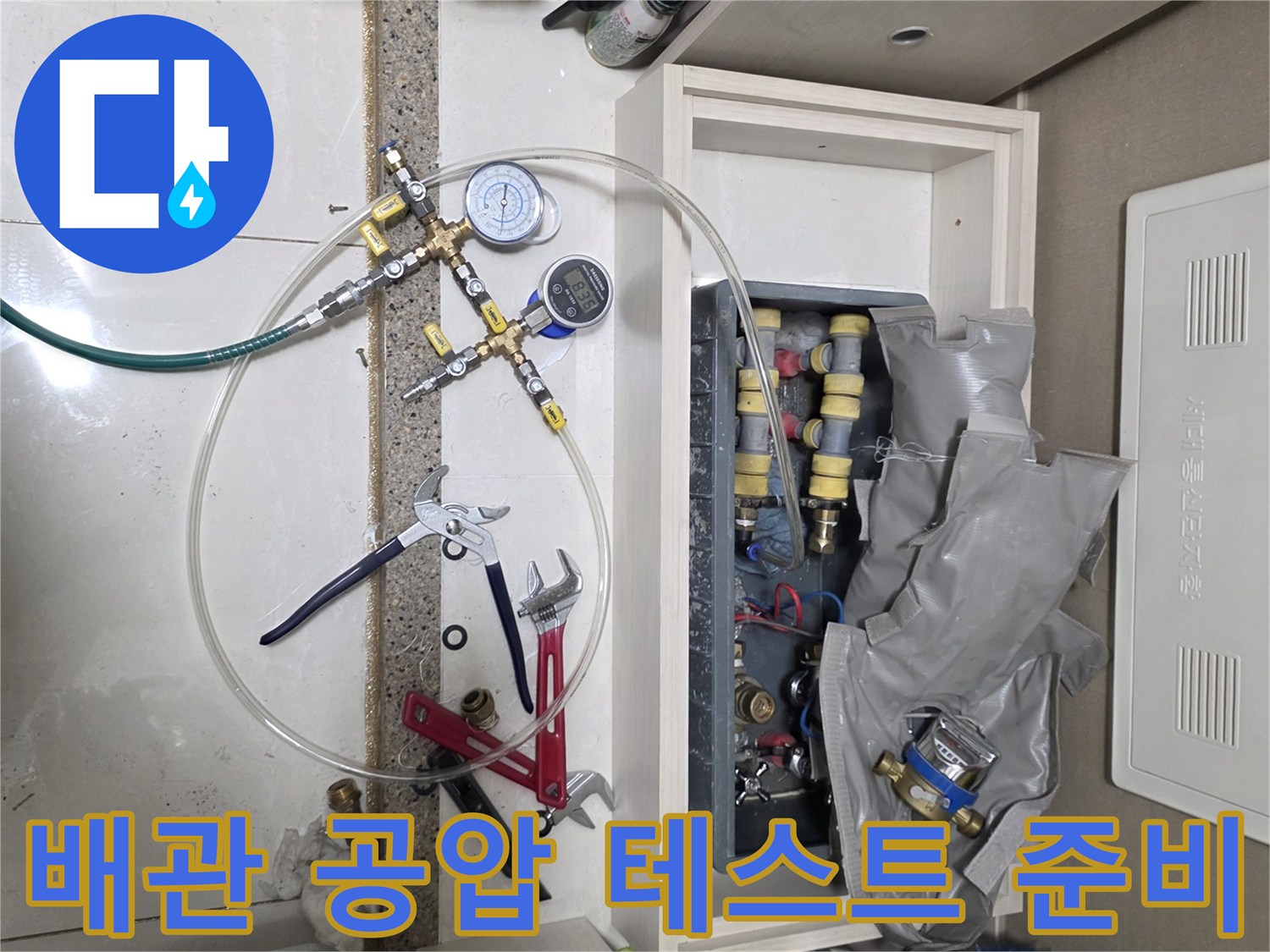 싱크대 하부 배관 점검을 위해 배치된 압력 게이지와 렌치 등 작업 도구