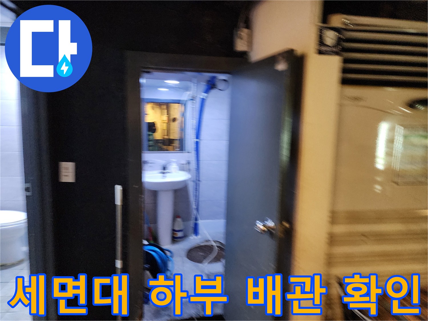 파란색 주름관과 세면대 밑 배관이 노출된 화장실 내부 전경