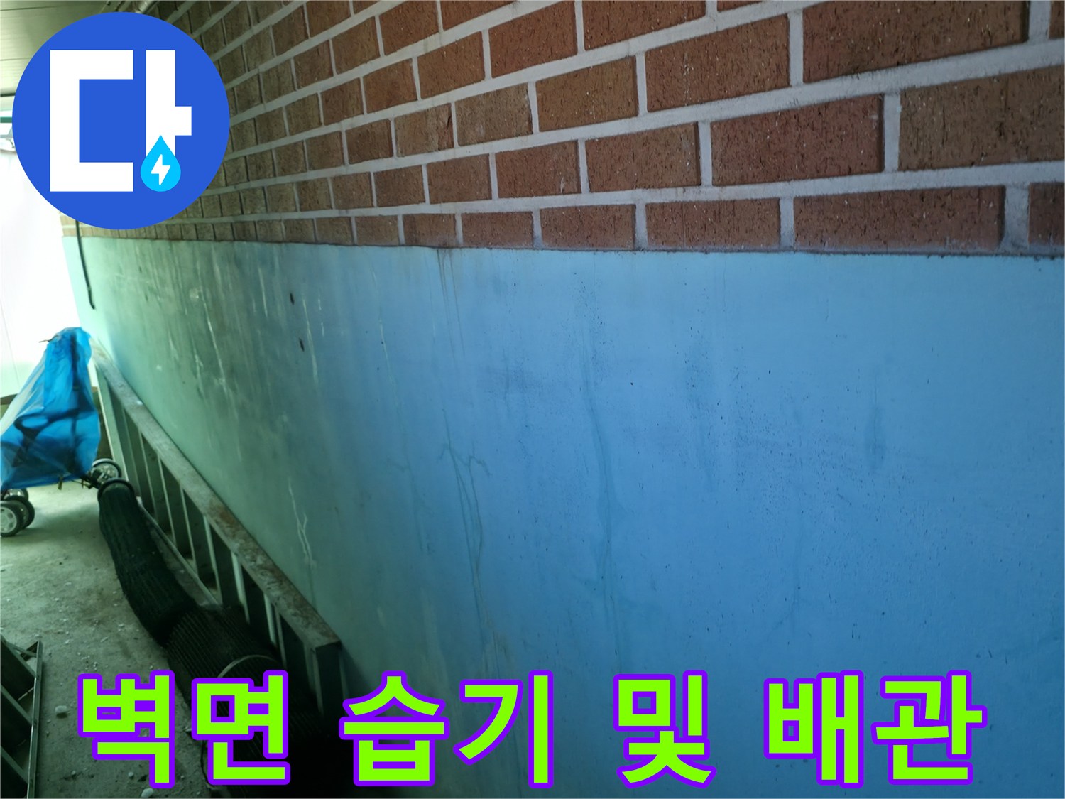 누수로 인해 젖은 벽돌 벽면과 노출된 점검 부위 배관