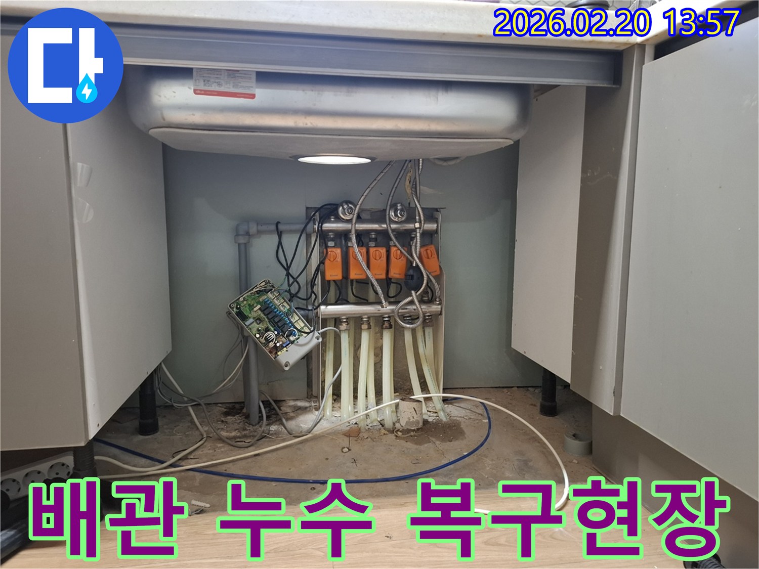 싱크대 하부의 복잡한 배관 시스템에서-발생한 누수 지점을 정확히 찾아내어-전문 엔지니어가 복구 작업을 진행하고 있습니다