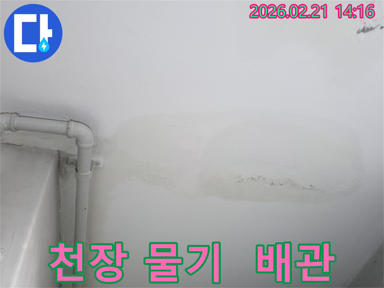 천장에 물기가 스며들어 얼룩진 모습과-그 옆으로 지나가는 배관이 함께 보이는 사진