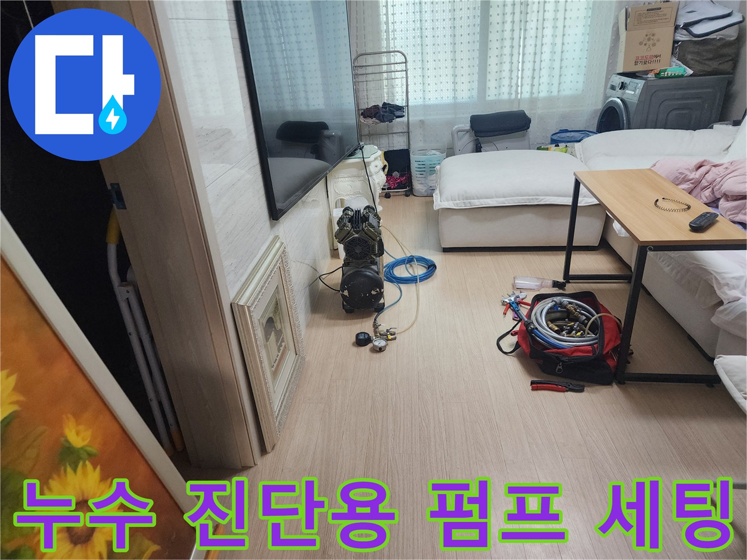 거실 바닥에 놓인 파란색 호스와 공기압 측정 장비 셋업