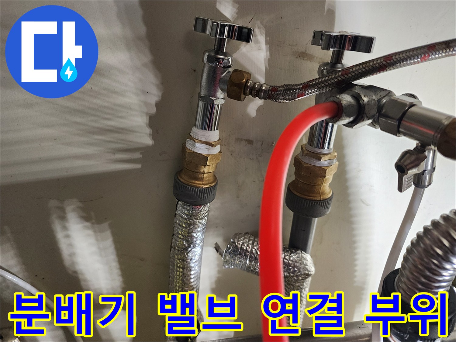 금속 밸브와 보온재가 설치된 난방 분배기 연결부 모습입니다.