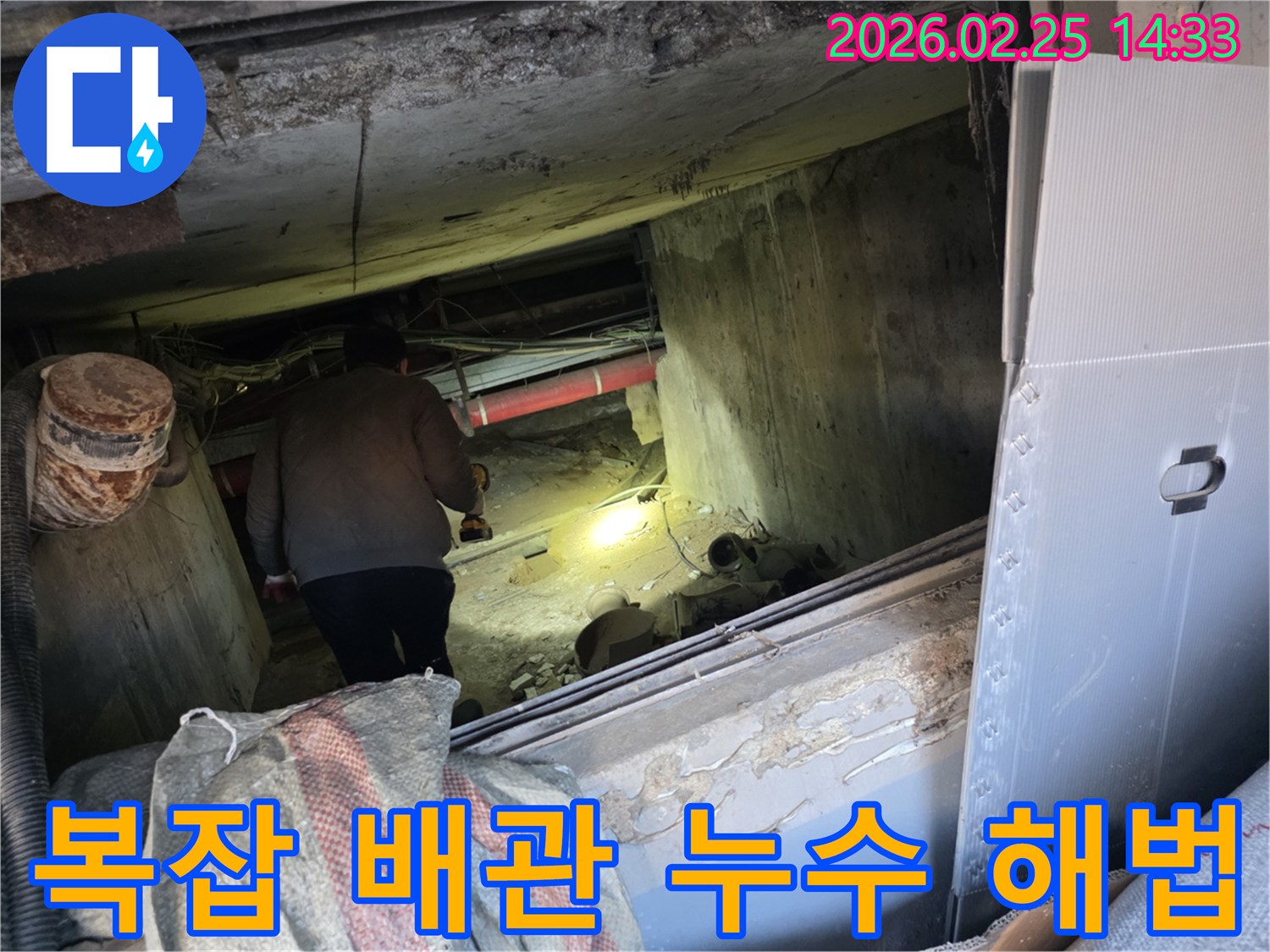 누수 전문 엔지니어가-어둡고 복잡하게 얽힌 배관 구조 속에서-손전등을 비춰-누수 지점을 찾아내고-해결책을 모색하는 모습입니다.
