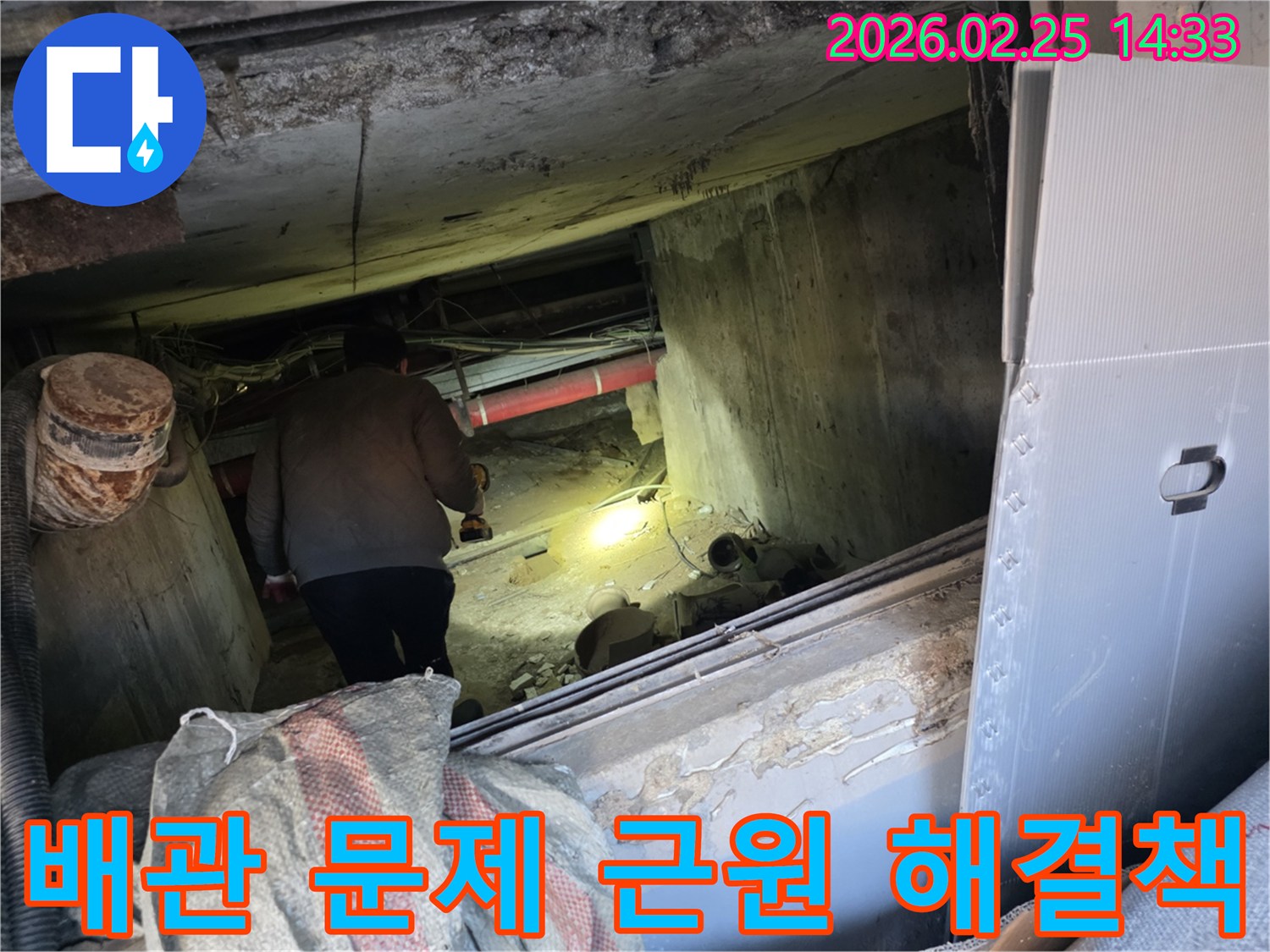 누수 전문 엔지니어가-어둡고 좁은 공간에서-손전등을 비춰가며-배관 문제의 근원적인 원인을-찾아내어 해결책을 제시하는 모습입니다.