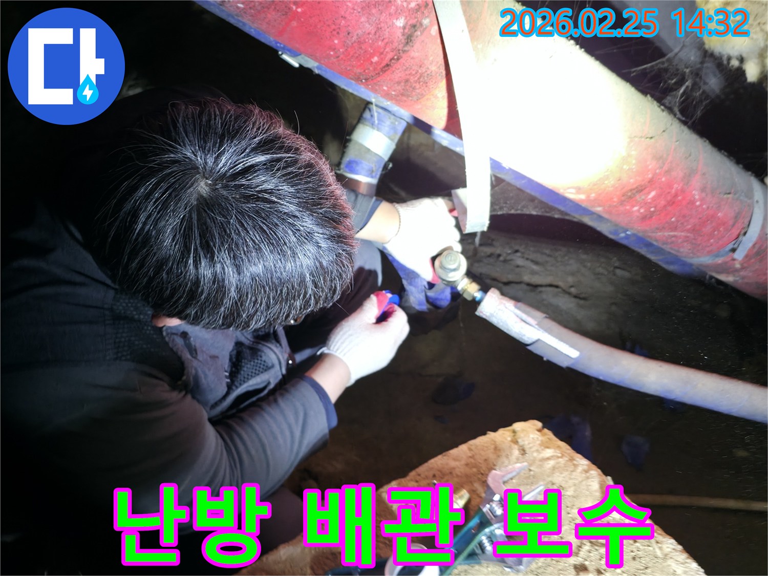 숙련된 누수 기술자가 좁은 공간에서 손전등을 비추며 난방 배관 연결 부위를 정밀하게 점검하고 보수하고 있습니다-난방누수해결-전문가보수