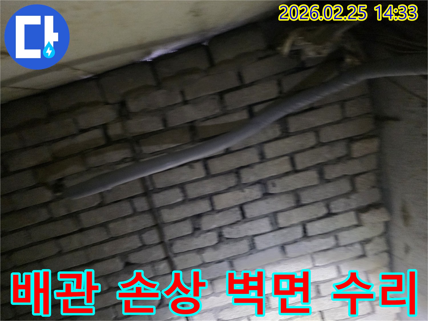 어두운 벽돌 벽면을 배경으로-손상된 배관과 함께-누수 수리 작업을 위해-정밀하게 검사되는 현장 모습입니다.