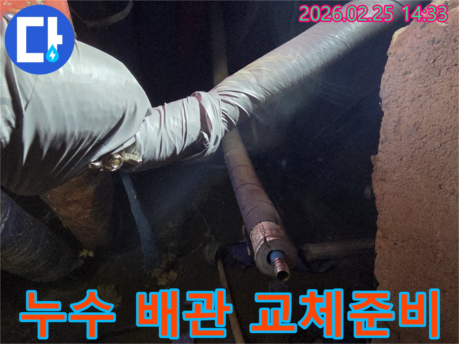 어두운 작업 환경에서-장갑을 낀 손이-손상된 배관을-새로운 부품으로-교체하기 위해-정교하게 준비하는-모습을 담고 있습니다