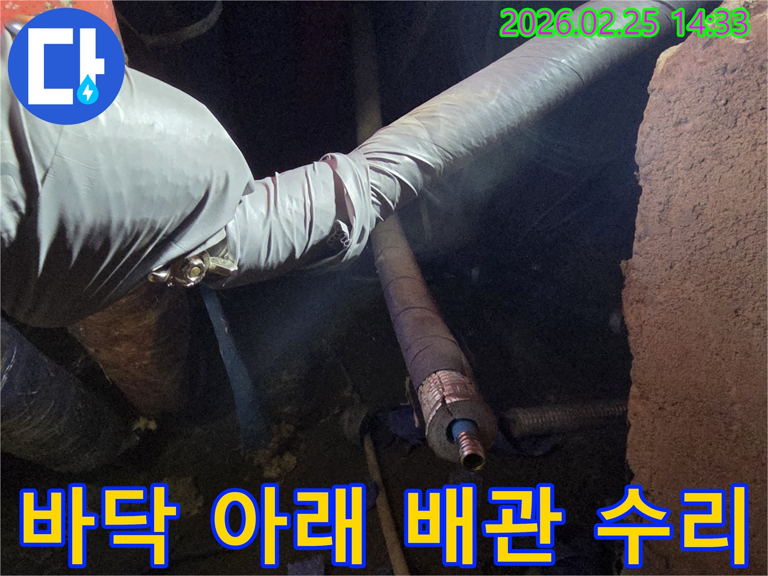 어둡고 좁은 바닥 아래-작업 공간에서-장갑을 낀 손이-배관의 누수 지점을-정밀하게 수리하는-모습입니다