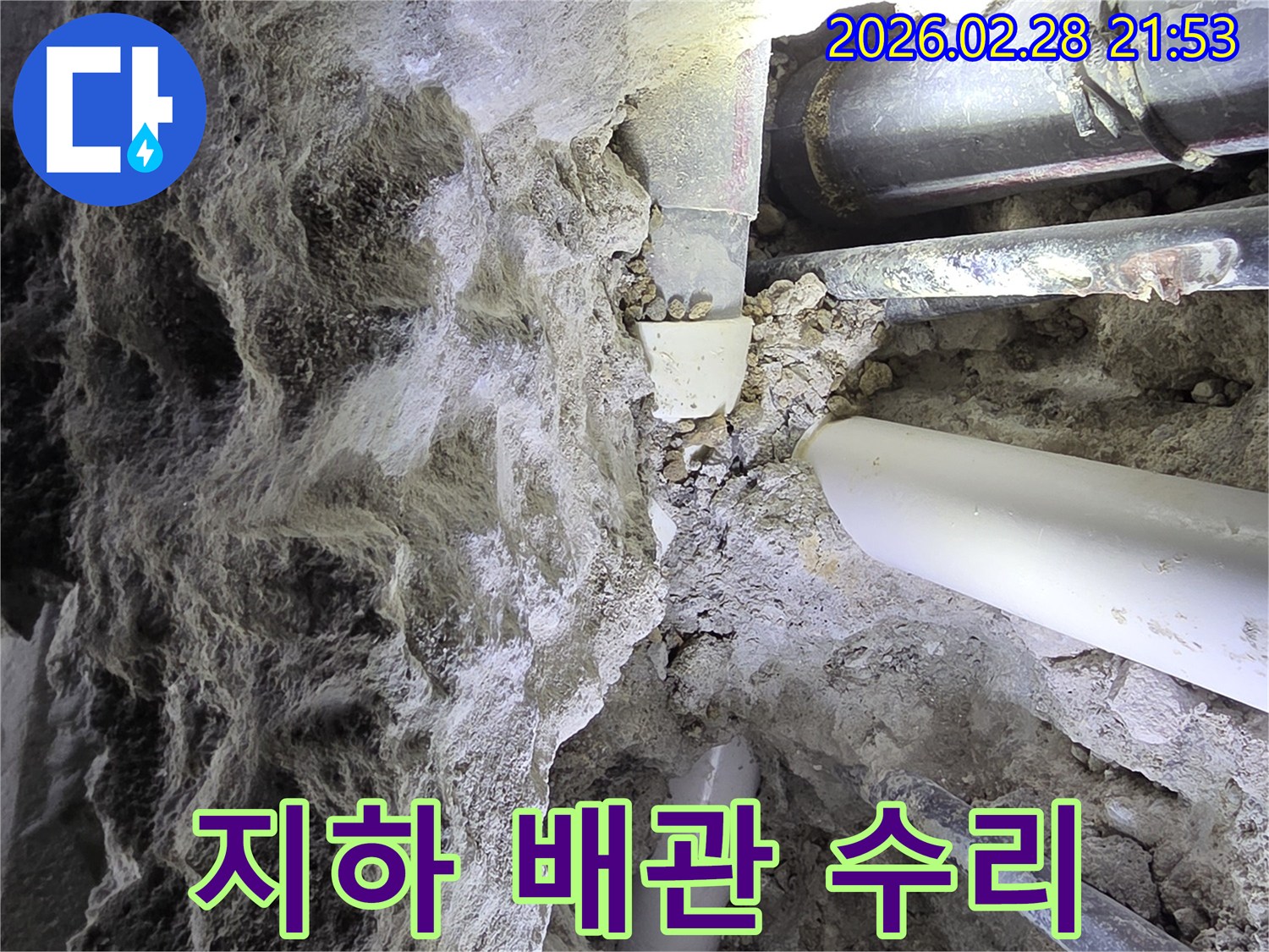 어두운 공간에서-흙과 자갈 속에 묻힌-다양한 배관들을-점검하는 누수 전문가의 모습