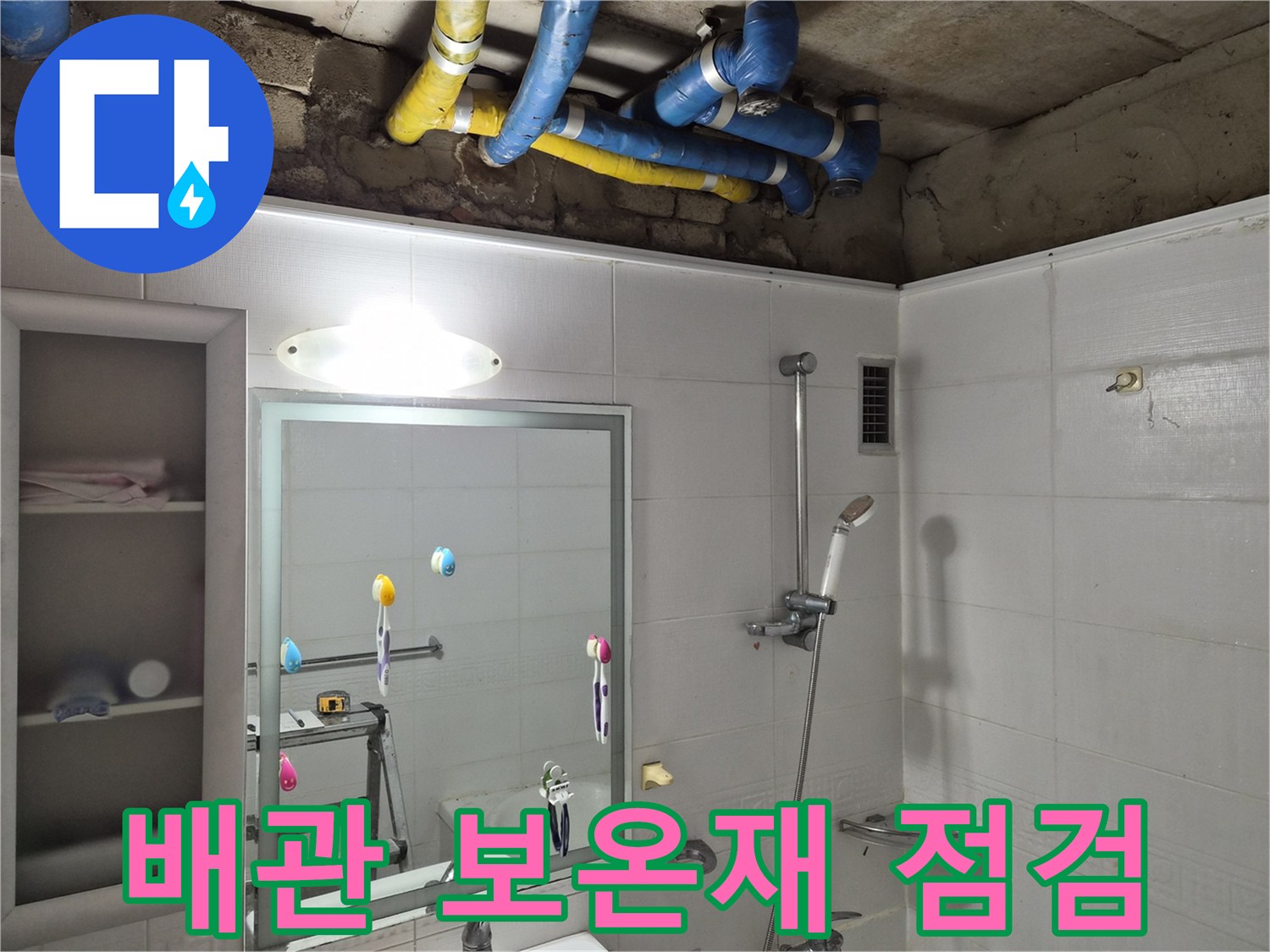 욕실 천장 내부의 파란색 및 노란색 배관 보온재와 콘크리트 천장면