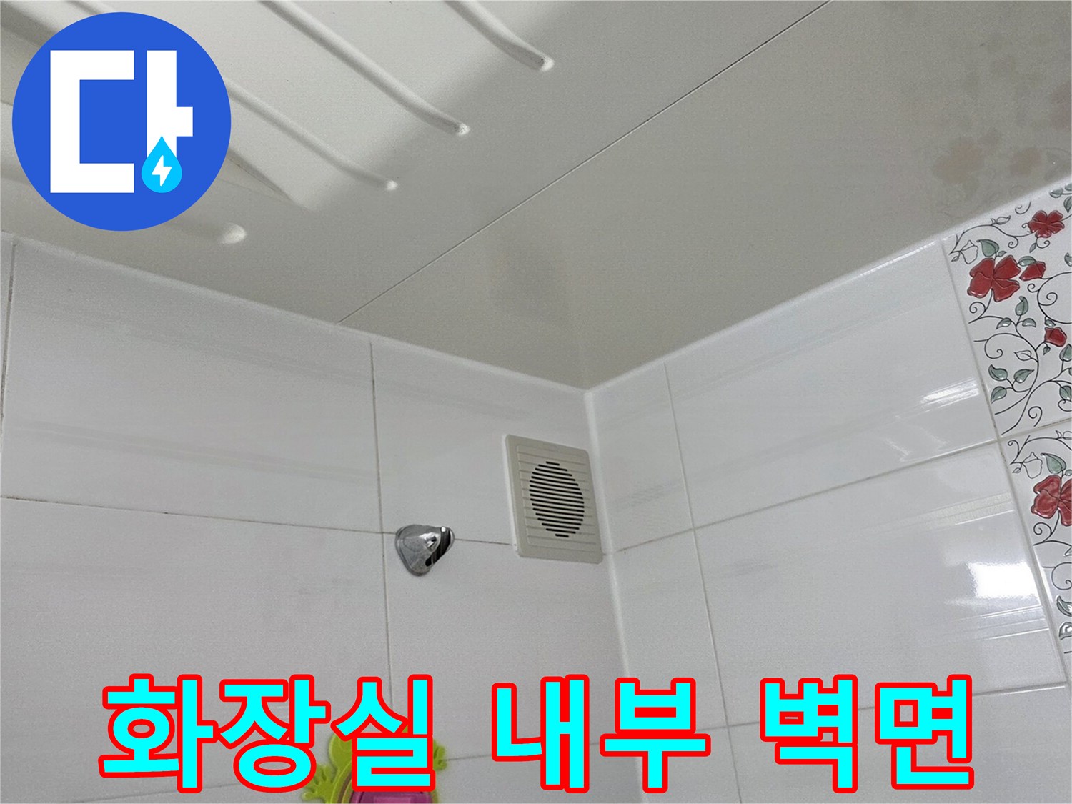 하얀색 타일로 마감된 화장실 벽면과 환풍기 근처 점검구 부위