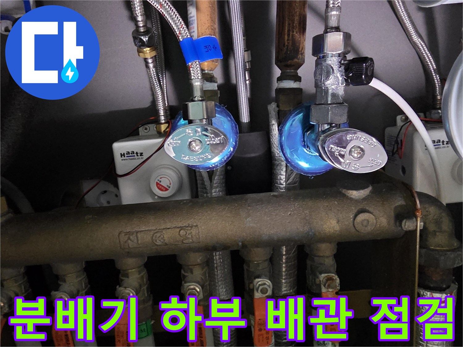 금속 분배기와 연결된 수도 밸브 및 압력 게이지의 근접 사진입니다.
