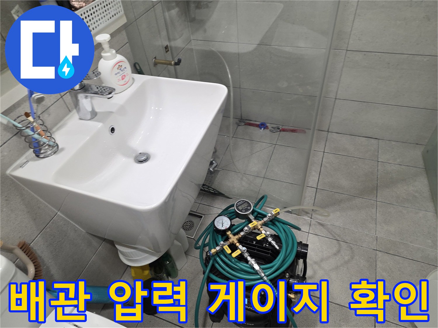 세면대 하단 공간-공압 테스트 장비와 호스 연결 상태