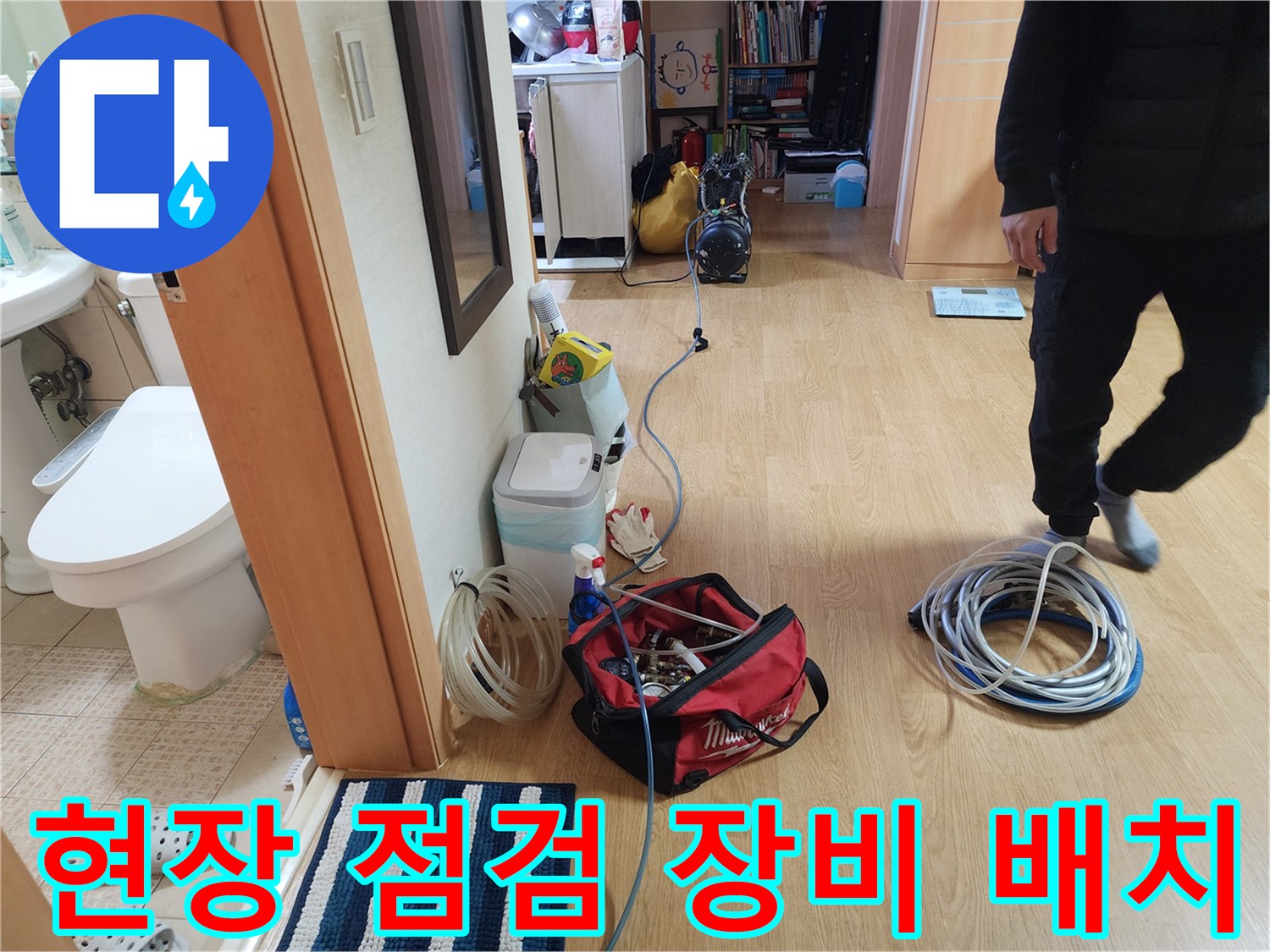 거실 바닥에 놓인 누수 탐지용 공압 기계와 연결 호스들